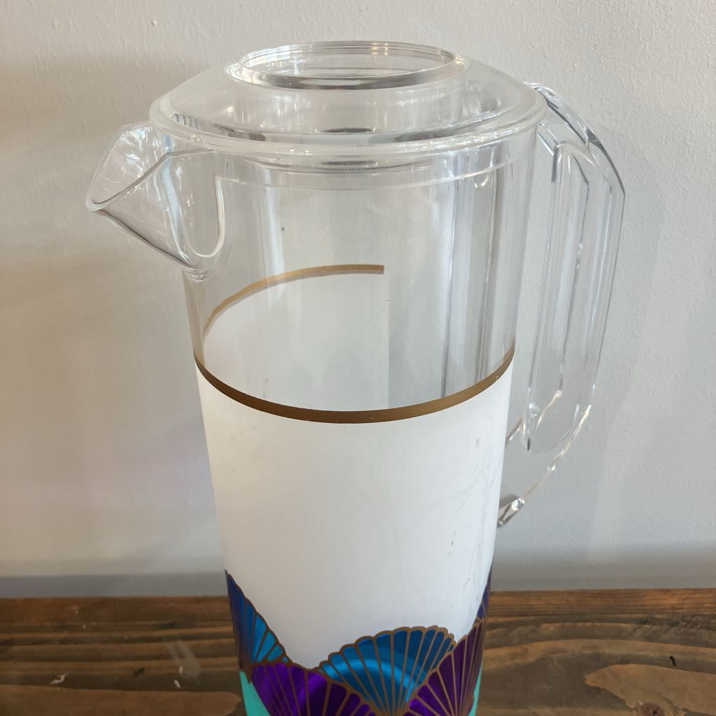 Clear plastic pitcher with decorative base on a wooden surface