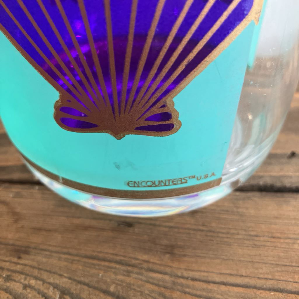 Plastic pitcher with purple and gold design on a wooden surface