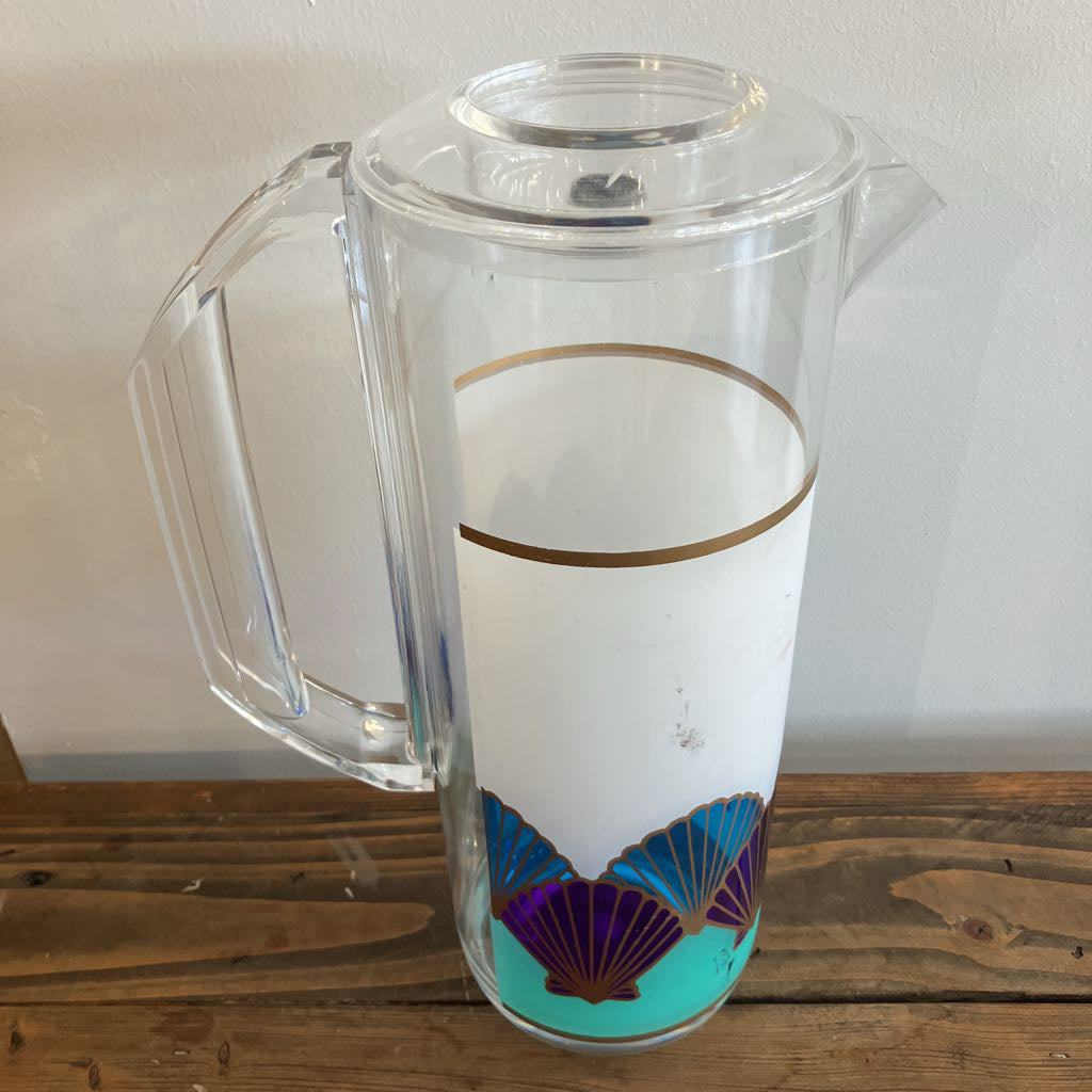 Clear glass pitcher with decorative design on a wooden surface