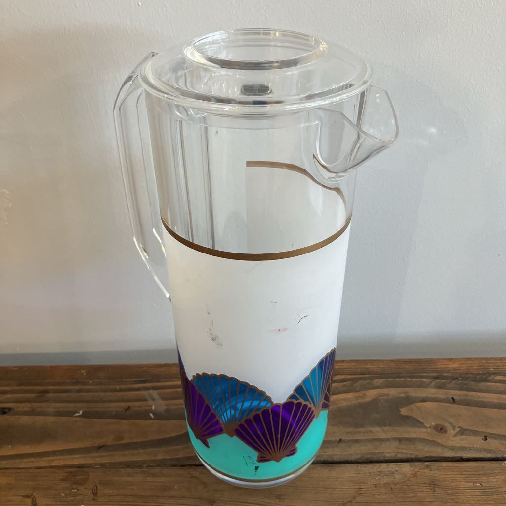 Clear pitcher with shell design on a wooden surface