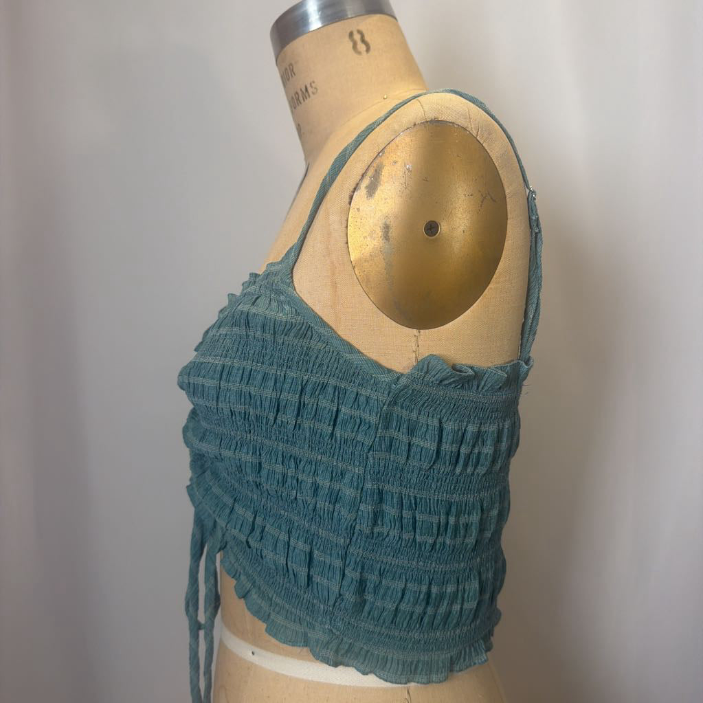 Green knitted crop top on a mannequin against a plain background