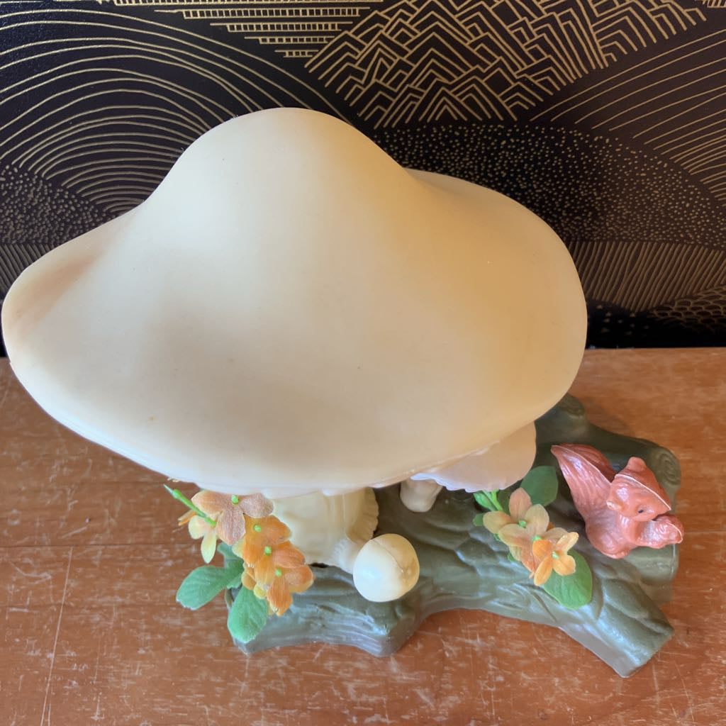 Decorative mushroom figurine with flowers and a butterfly on a wooden surface