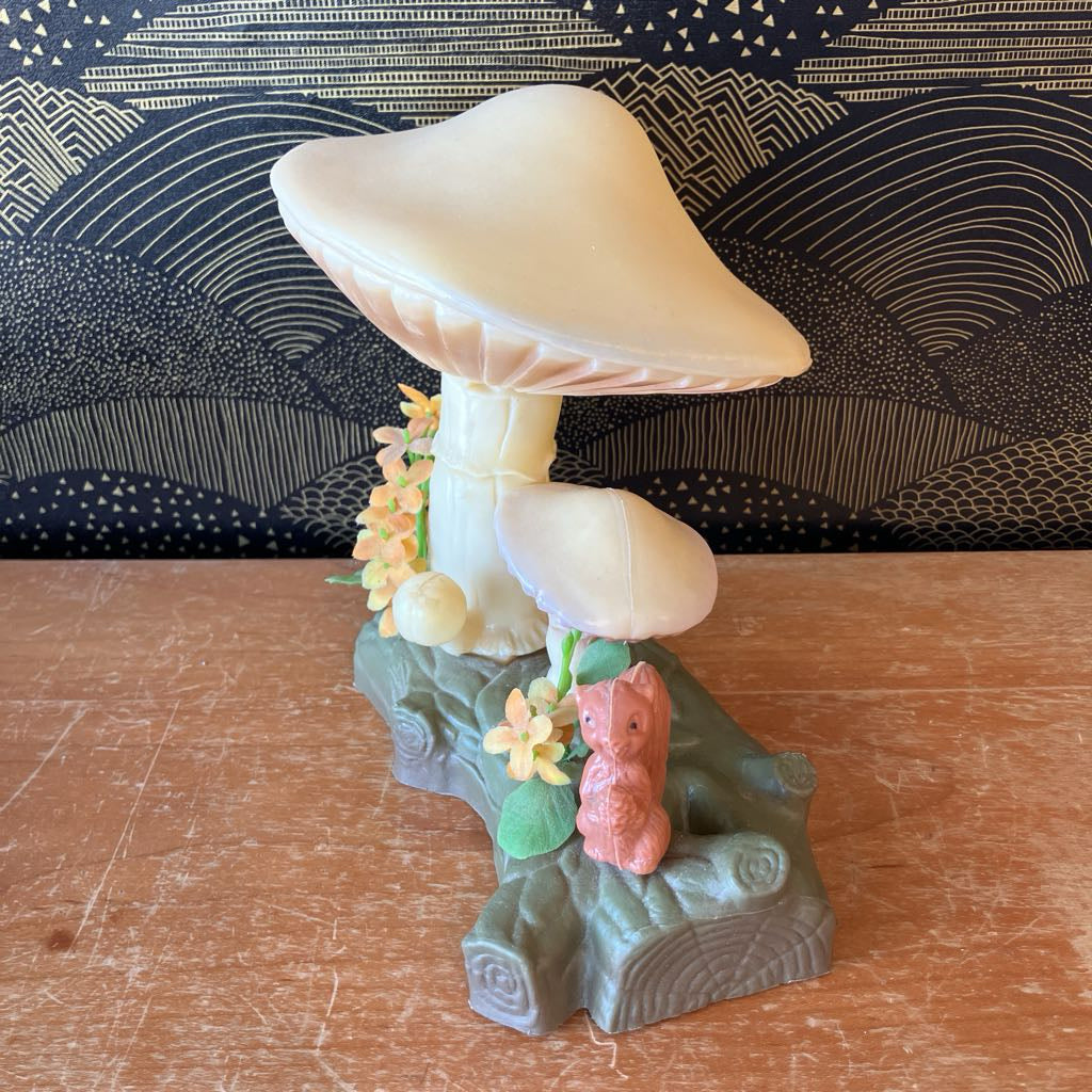 Decorative mushroom figurine with flowers and a squirrel on a wooden surface.