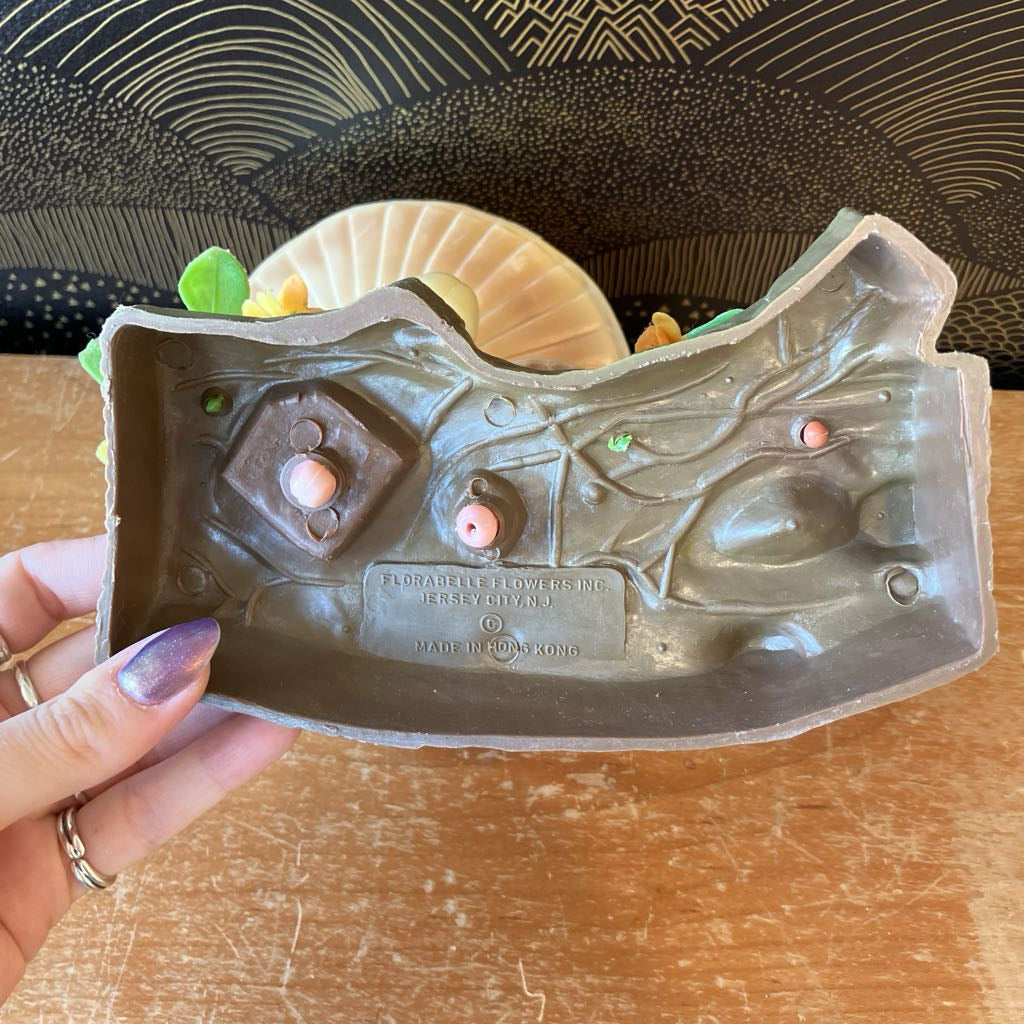 Blow mold held by a hand on a wooden surface with a decorative background.