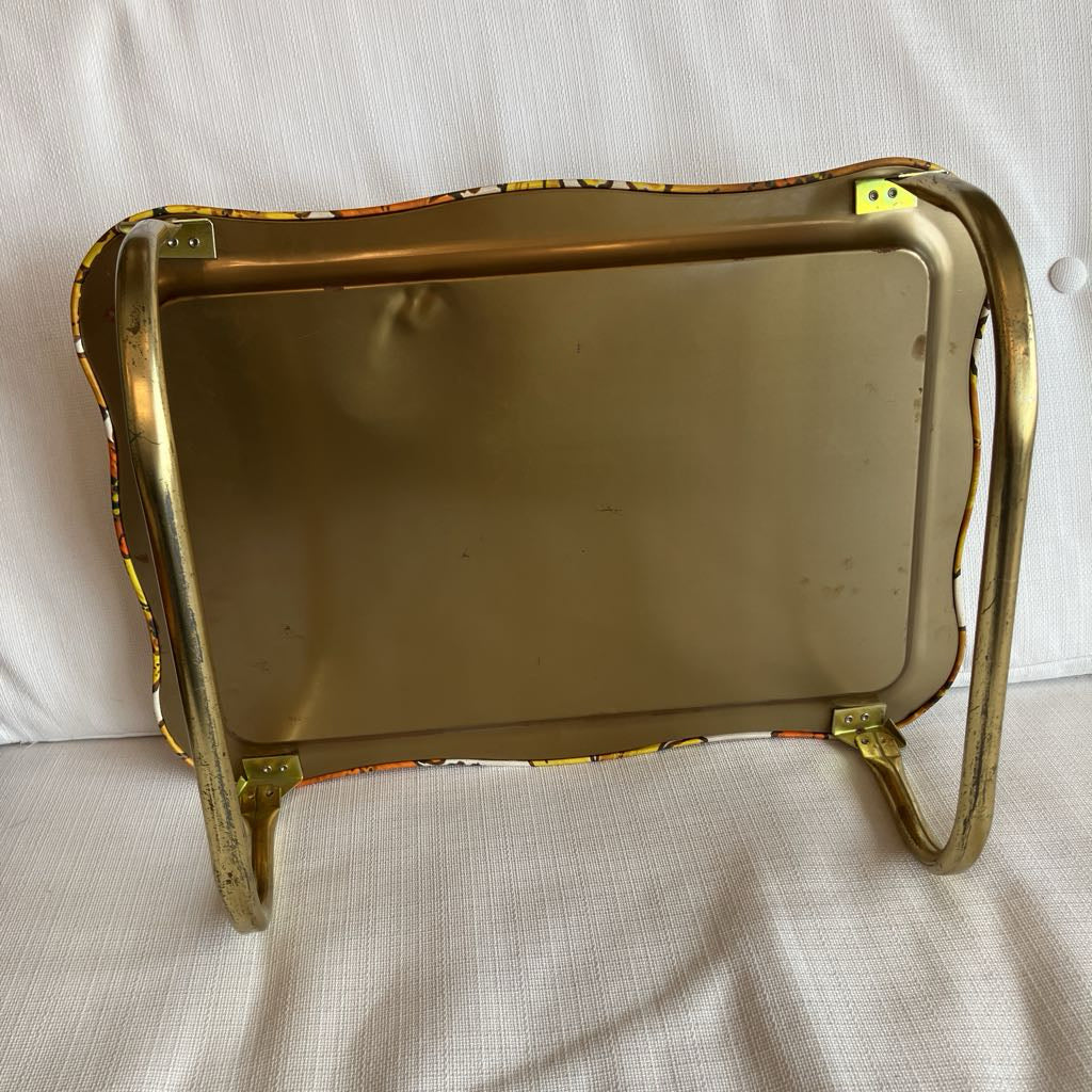 The bottom of a metal T.V. tray on a white surface.