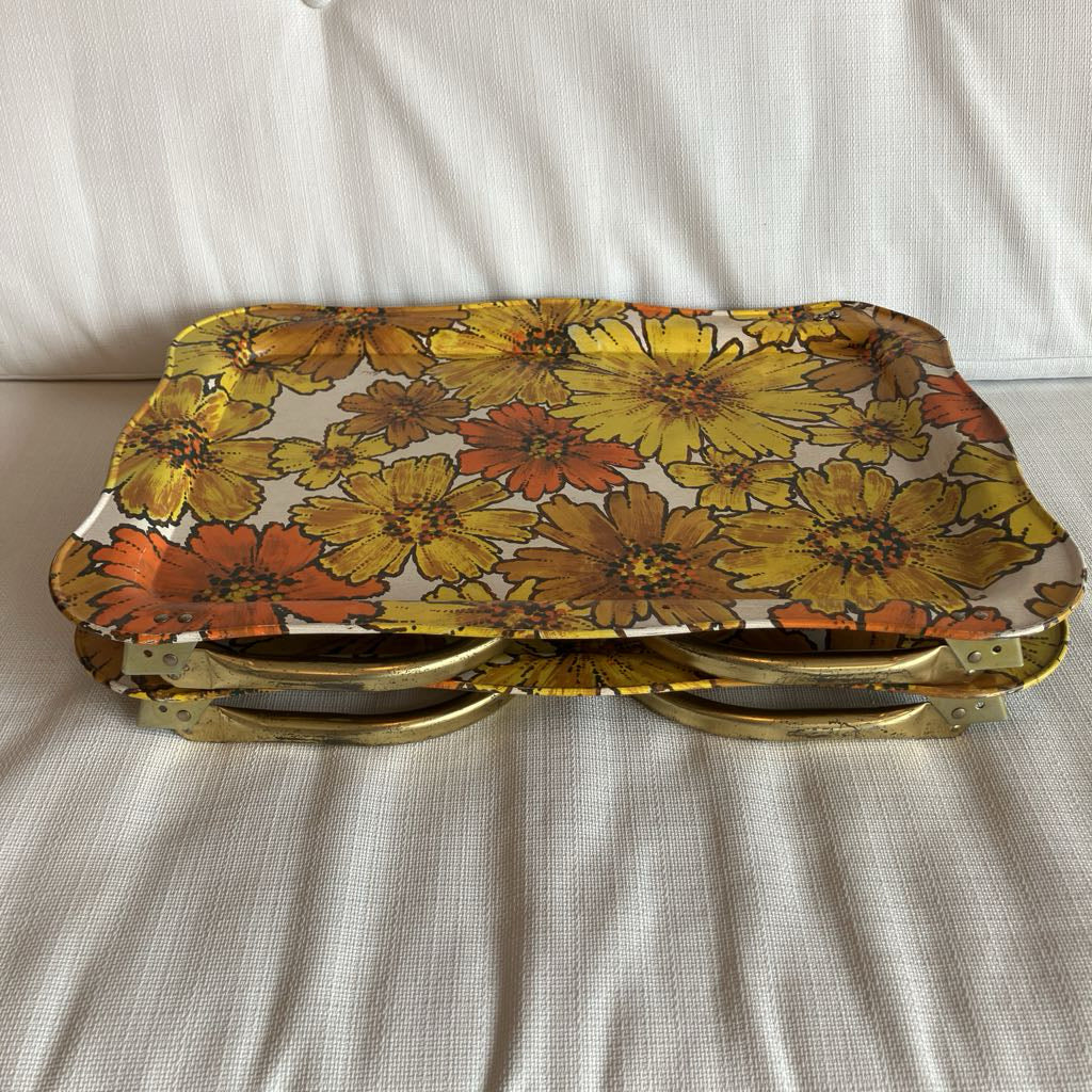 Floral-patterned trays with gold rims stacked on a white surface