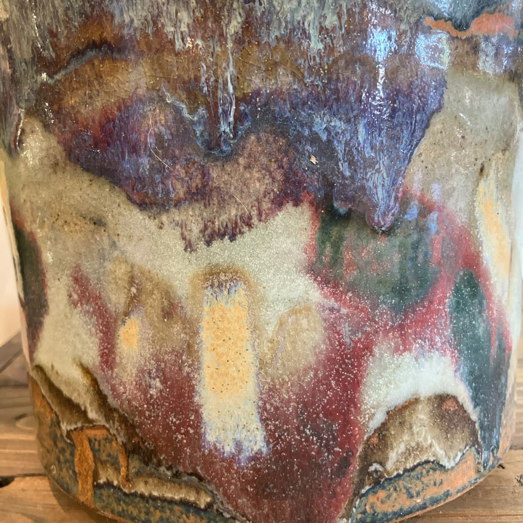 Close-up of a ceramic vase with multicolored glaze on a wooden surface