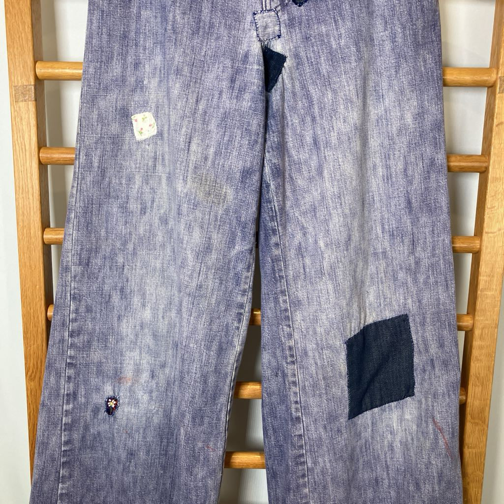 Pair of blue jeans with patches on a wooden rack