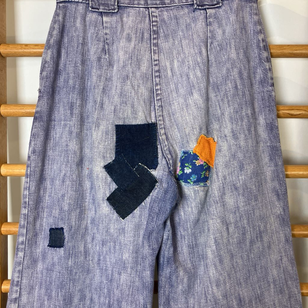 Blue denim jeans with patches on a wooden rack