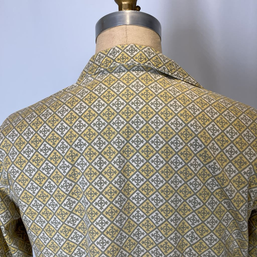 Mannequin wearing a patterned shirt with a geometric design on a plain background
