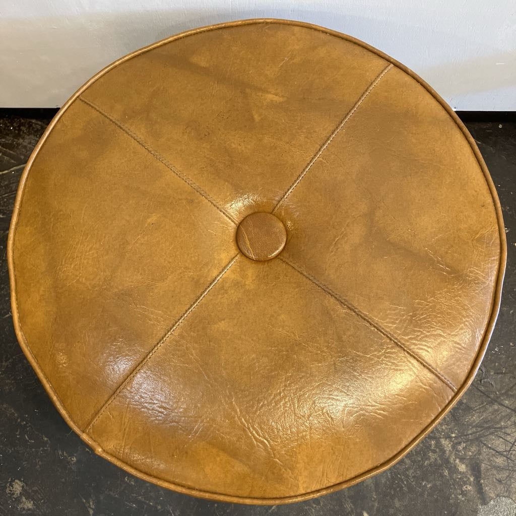Round brown leather ottoman on a dark surface