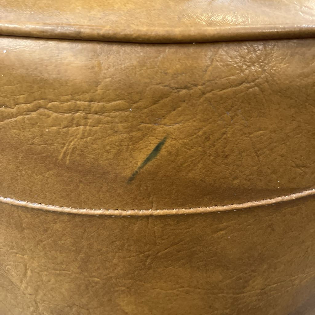 Close-up of a brown leather ottoman with visible wear and tear.