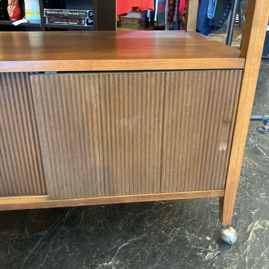 Wooden sideboard with ribbed design on a black marble floor