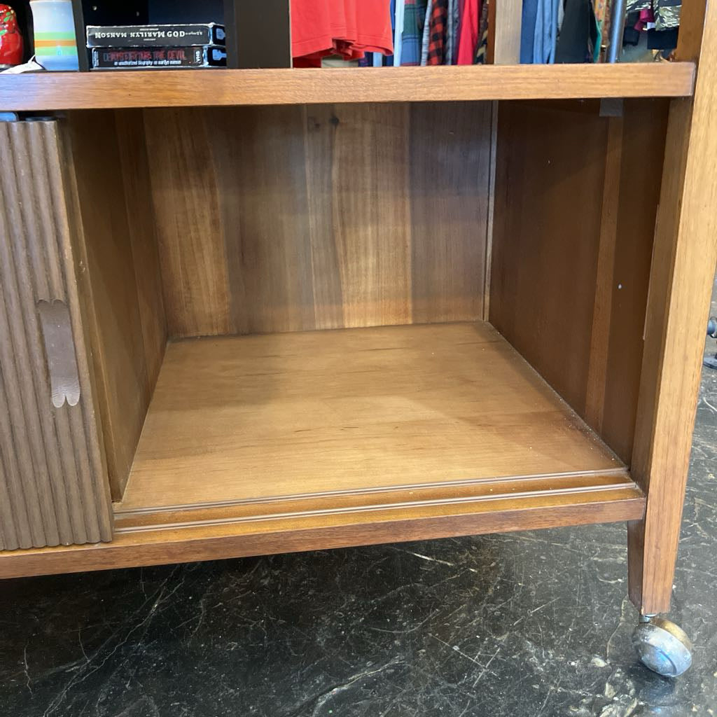 Wooden shelf with a single book on a black marble floor