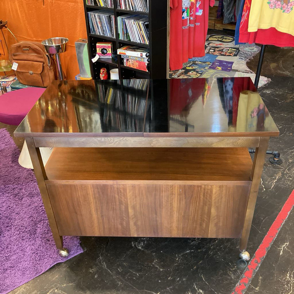 Wooden bar cart with glass top in a store setting