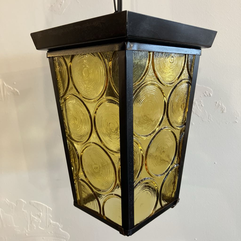 Decorative hanging light fixture with circular glass panels on a plain background