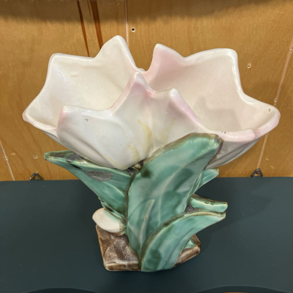 Ceramic flower-shaped egg holder with green leaves on a dark surface.