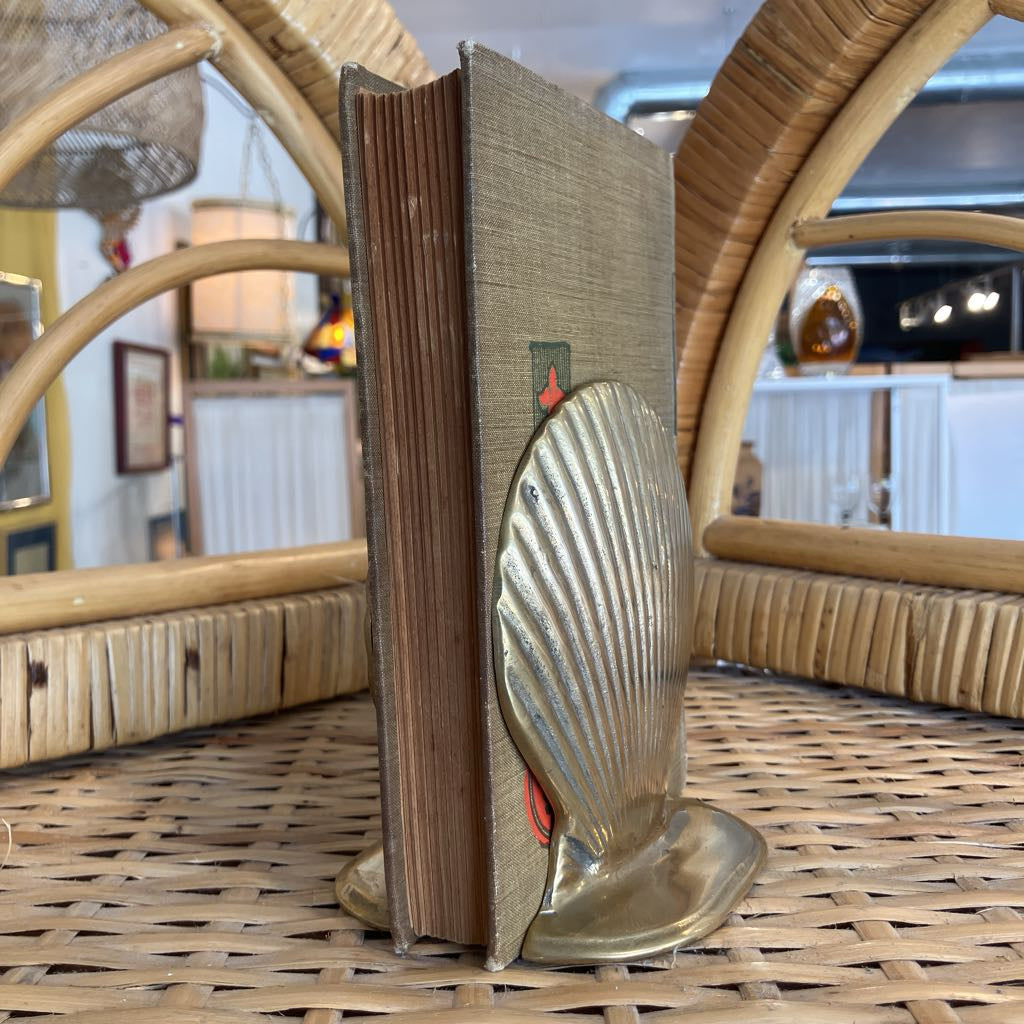 Brass shell bookends on either side of a book.