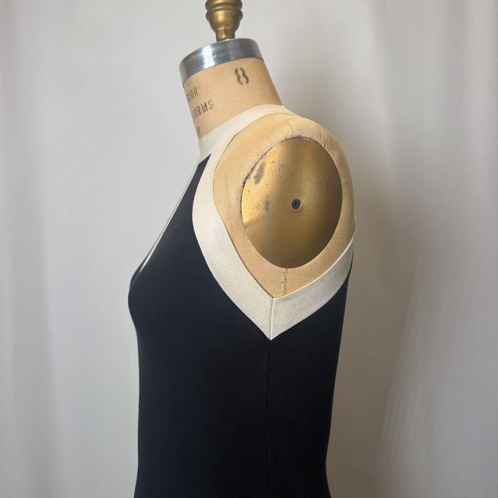 Black dress on a mannequin with a white collar against a plain background