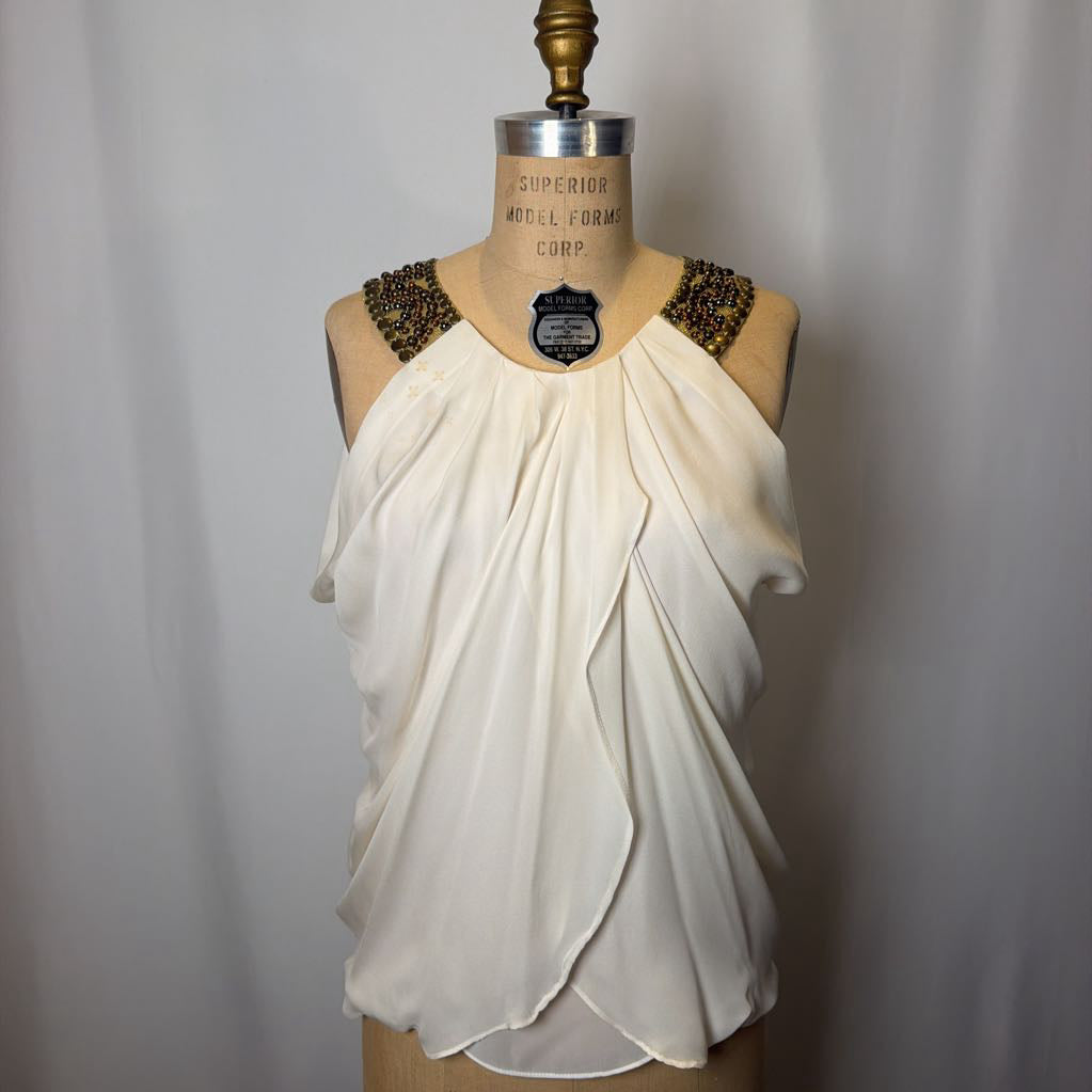 White draped top on a mannequin with a plain background