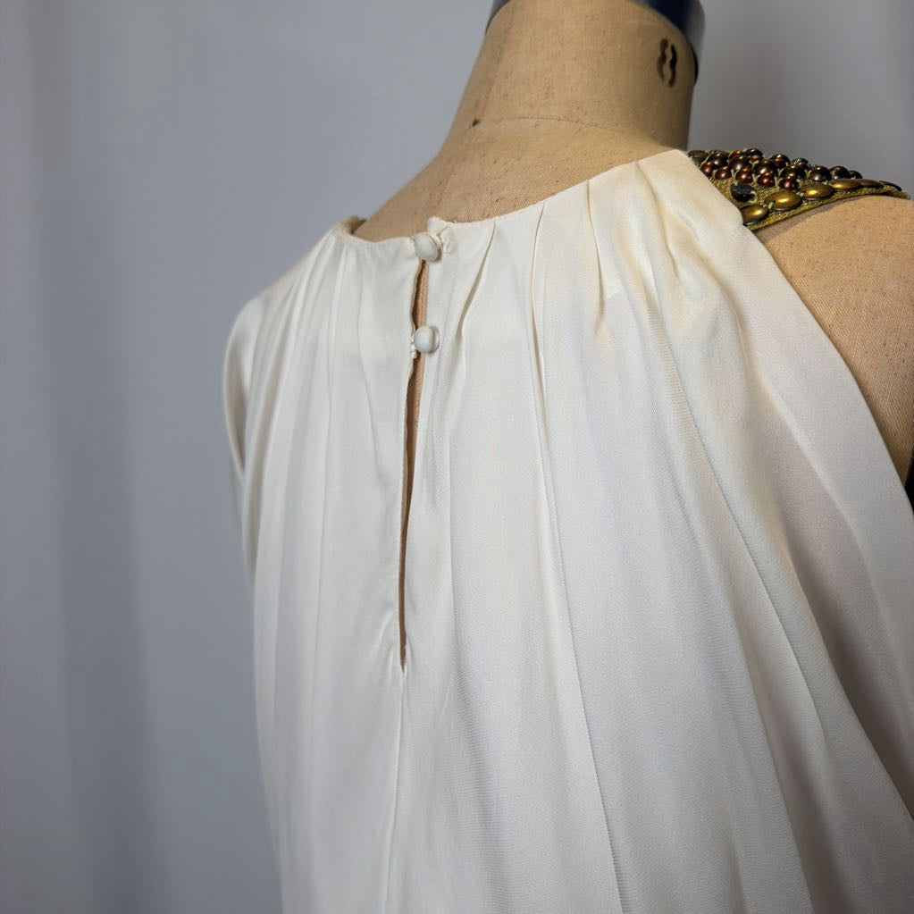 Mannequin wearing a white dress with a gold headpiece against a plain background