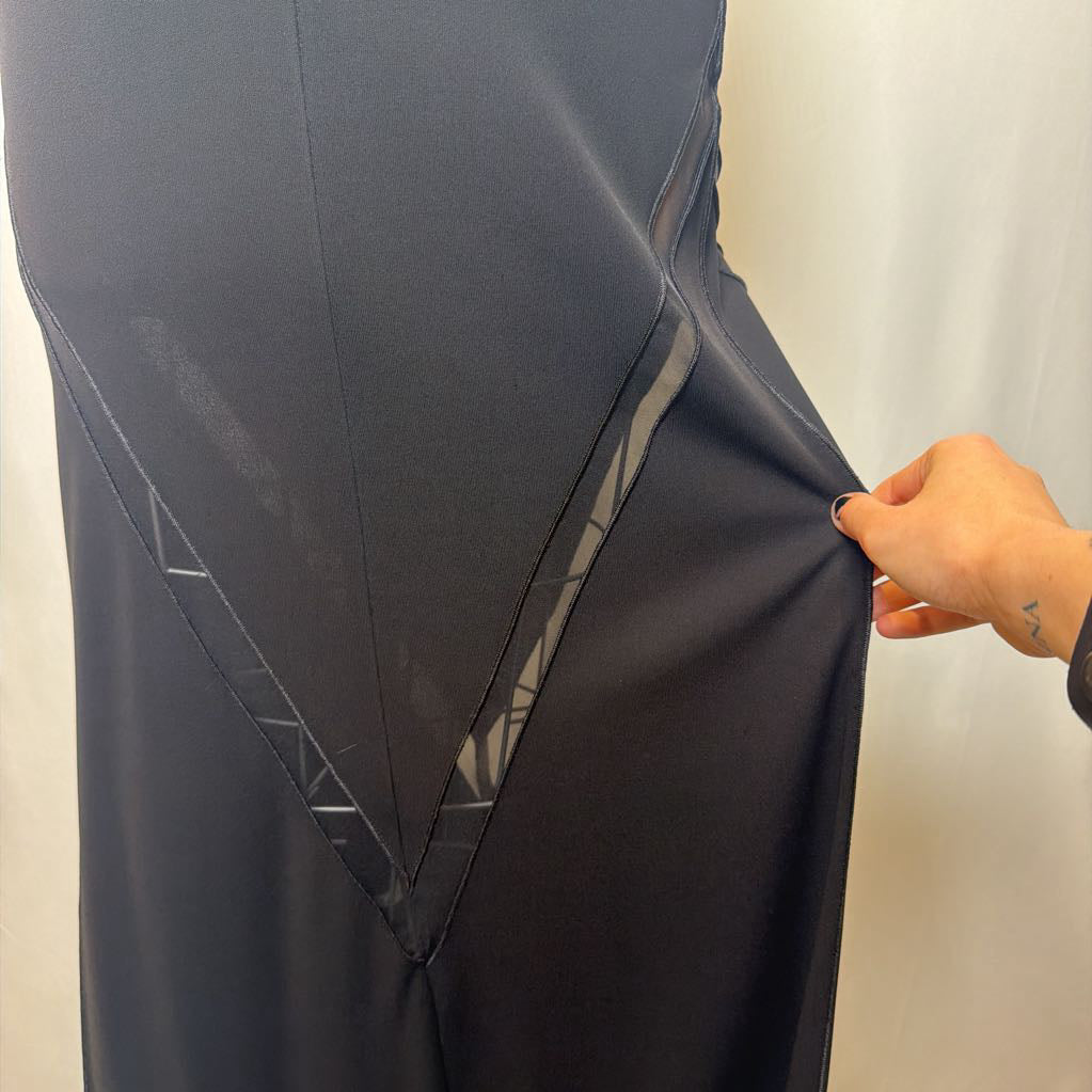 Dark gray fabric with geometric patterns held by a hand against a neutral background