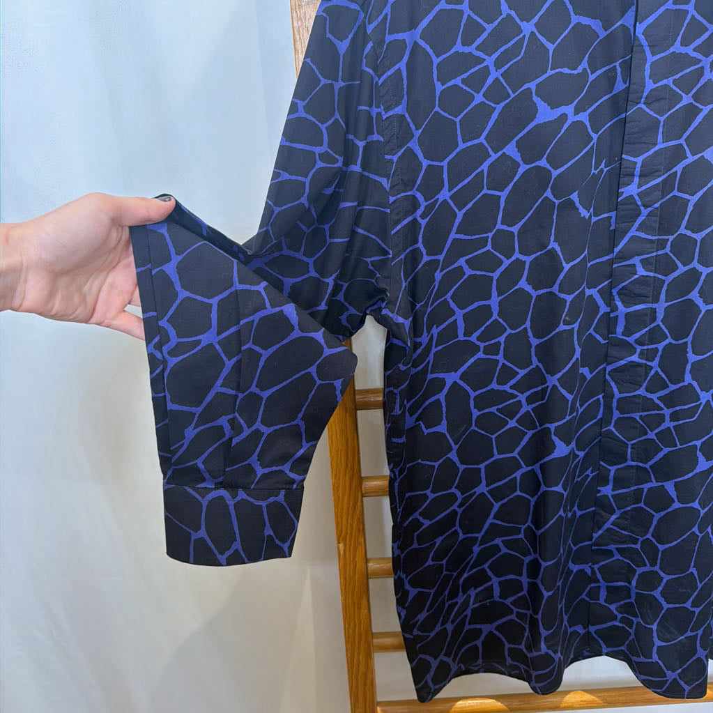 Blue patterned dress on a rack with a hand holding a matching blue bralette.