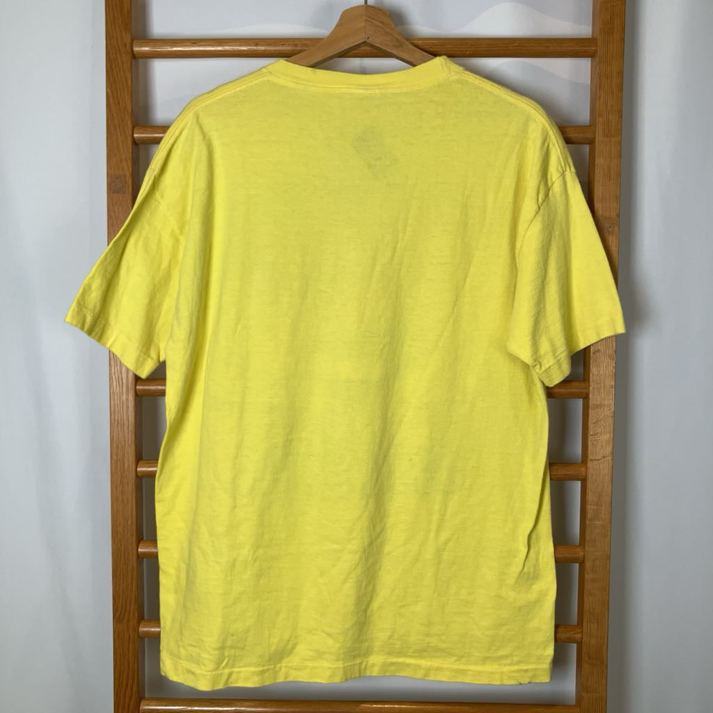 Yellow t-shirt on a wooden hanger against a white wall