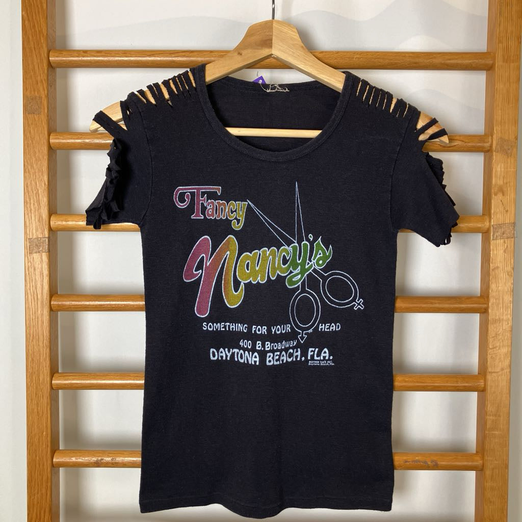 Black t-shirt with colorful graphic and text on a wooden rack