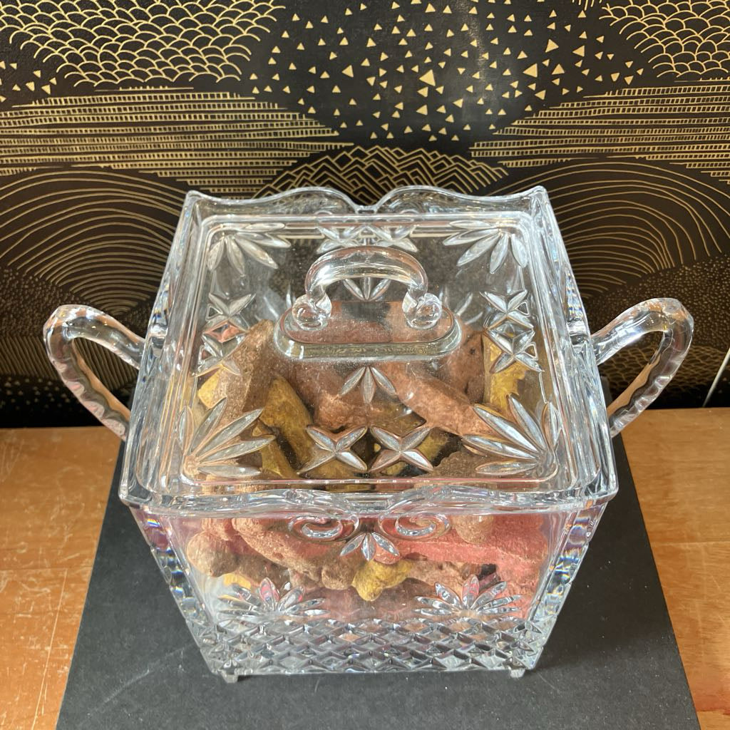 Decorative glass candy dish with lid on a wooden surface