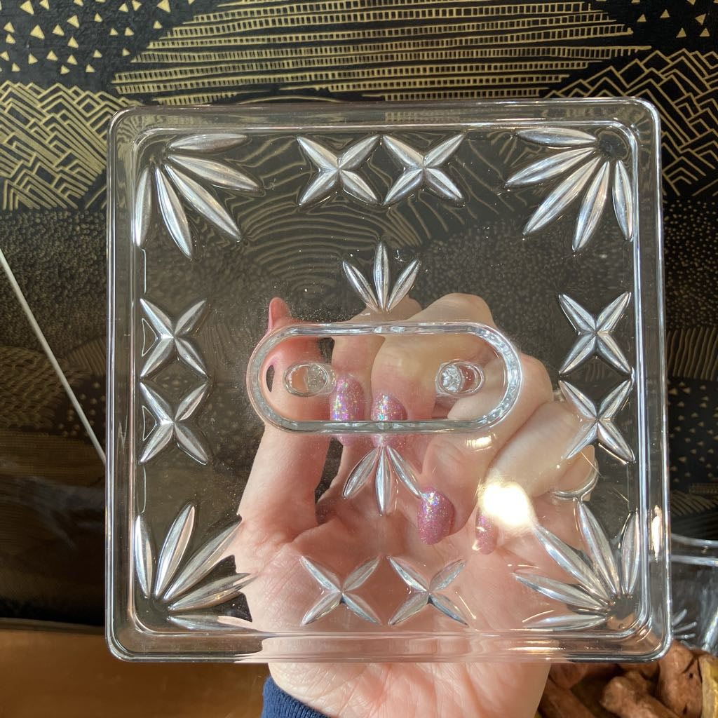 Hand holding a small glass block with star patterns against a dark background