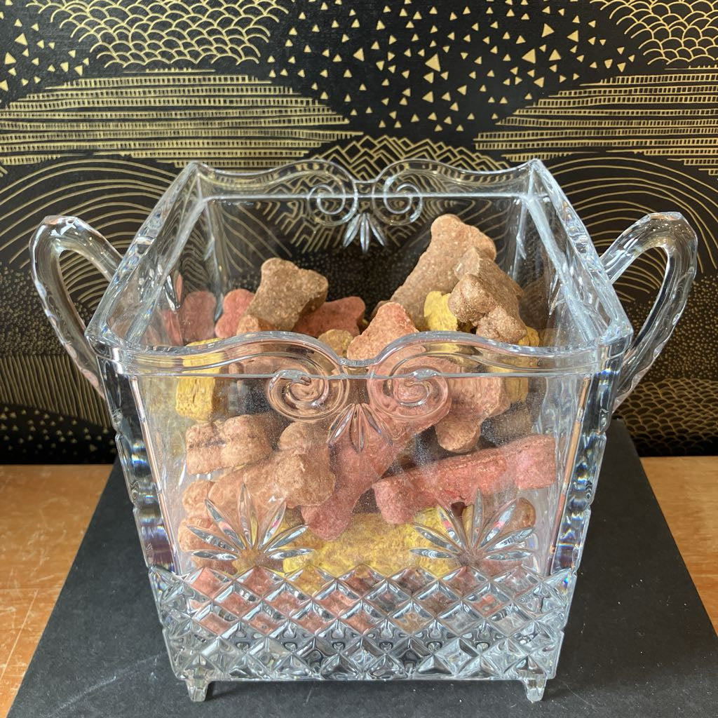 Clear glass candy dish with colorful gummy bears on a black surface.