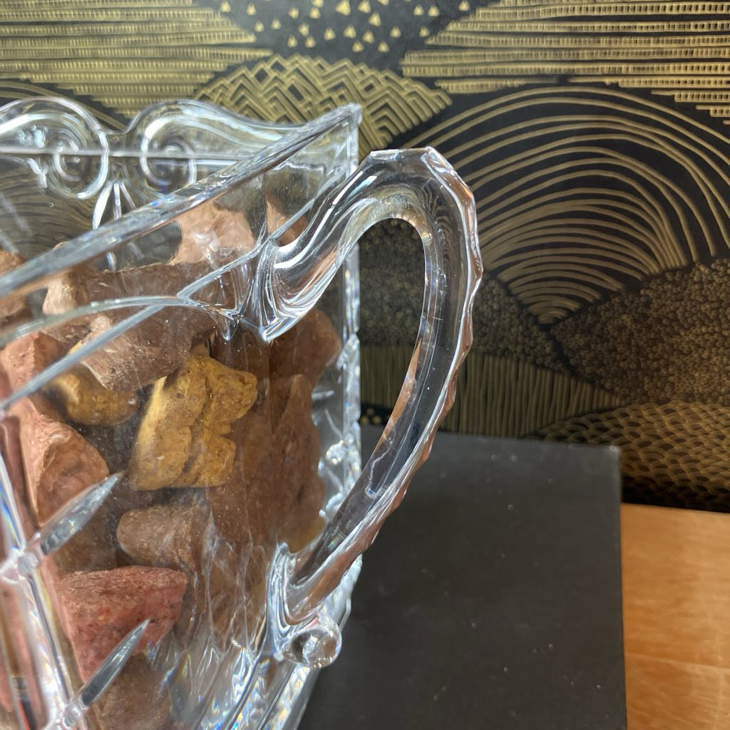 Clear glass container with wooden sticks inside, against a decorative background