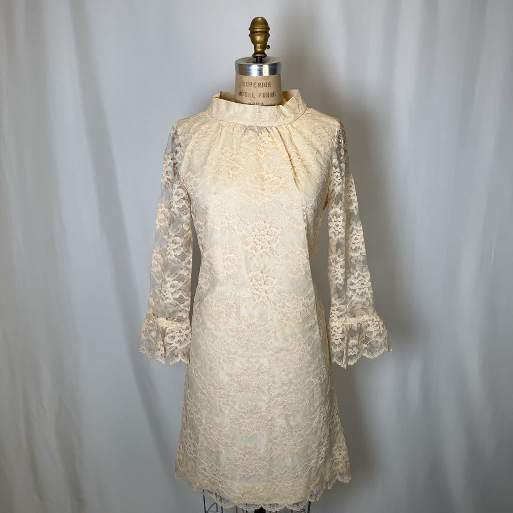 Vintage lace dress on a mannequin against a plain background