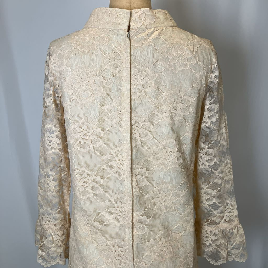 Beige lace blouse on a mannequin against a gray background