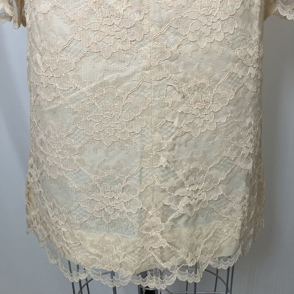 Close-up of a beige lace garment on a mannequin against a plain background