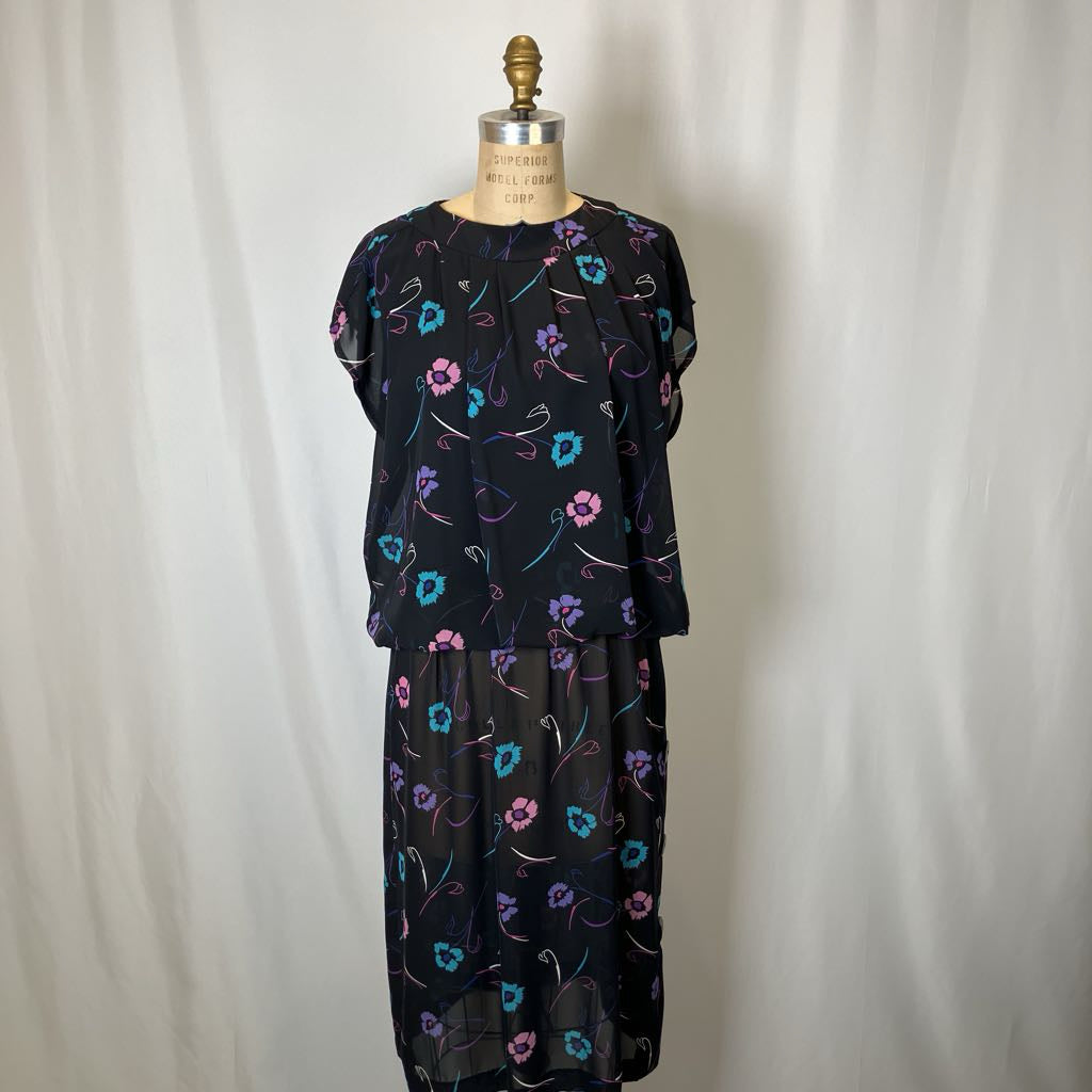 Black dress with colorful floral pattern on a mannequin against a white background