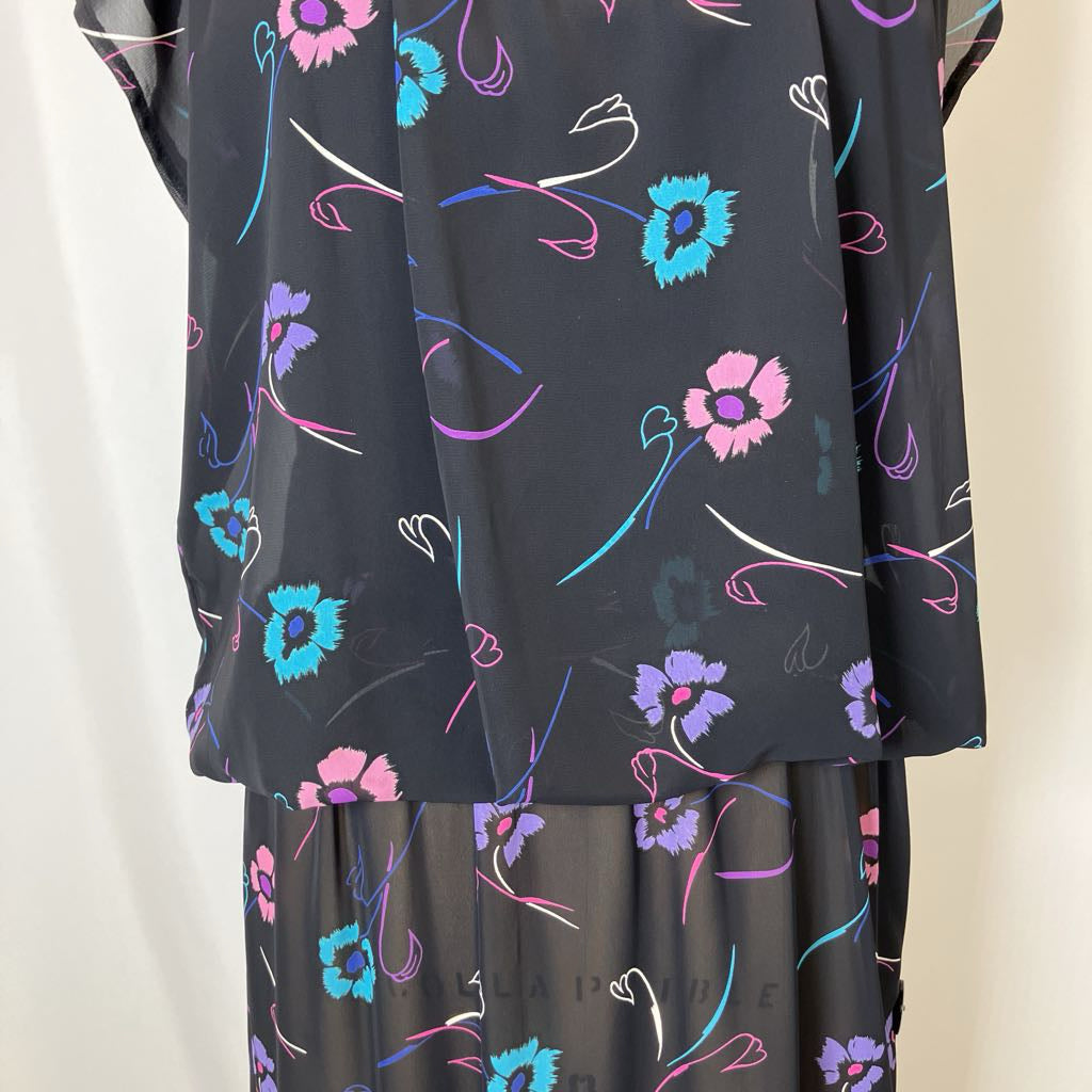 Black fabric with colorful floral and abstract patterns on a neutral background