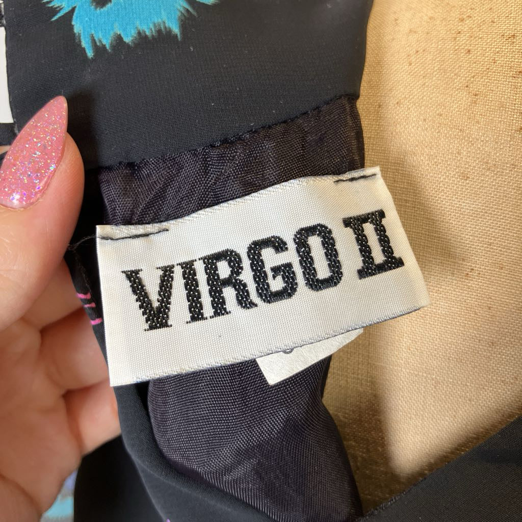 Label with 'VIRGO II' text on a garment, held by a hand with pink nail polish.