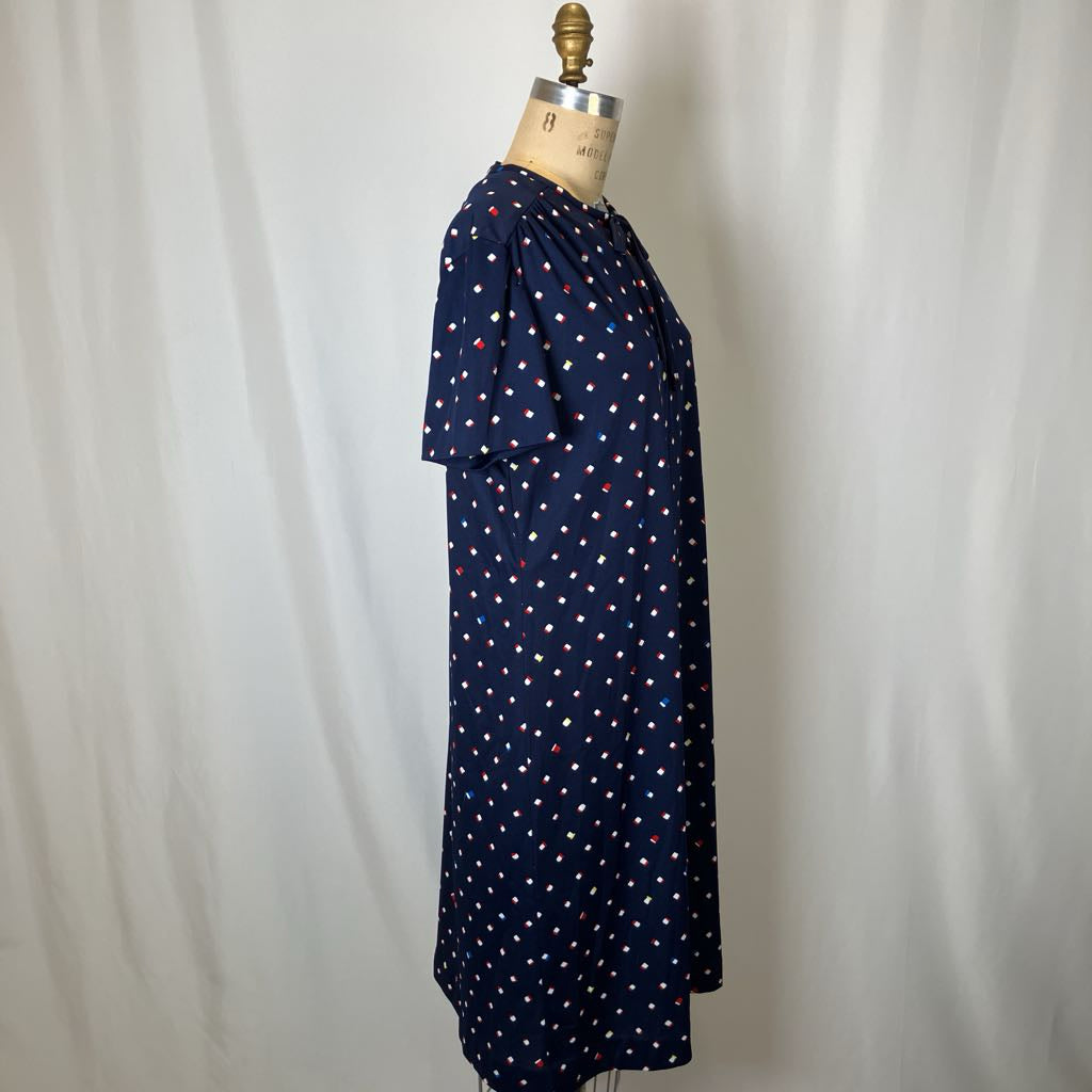 Navy dress with white polka dots on a mannequin against a plain background
