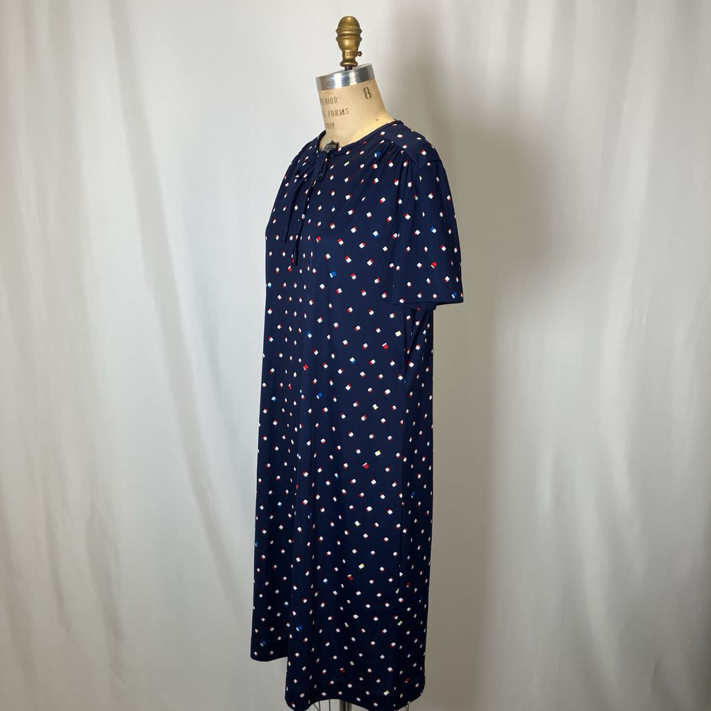 Navy blue dress with white polka dots on a mannequin against a plain background