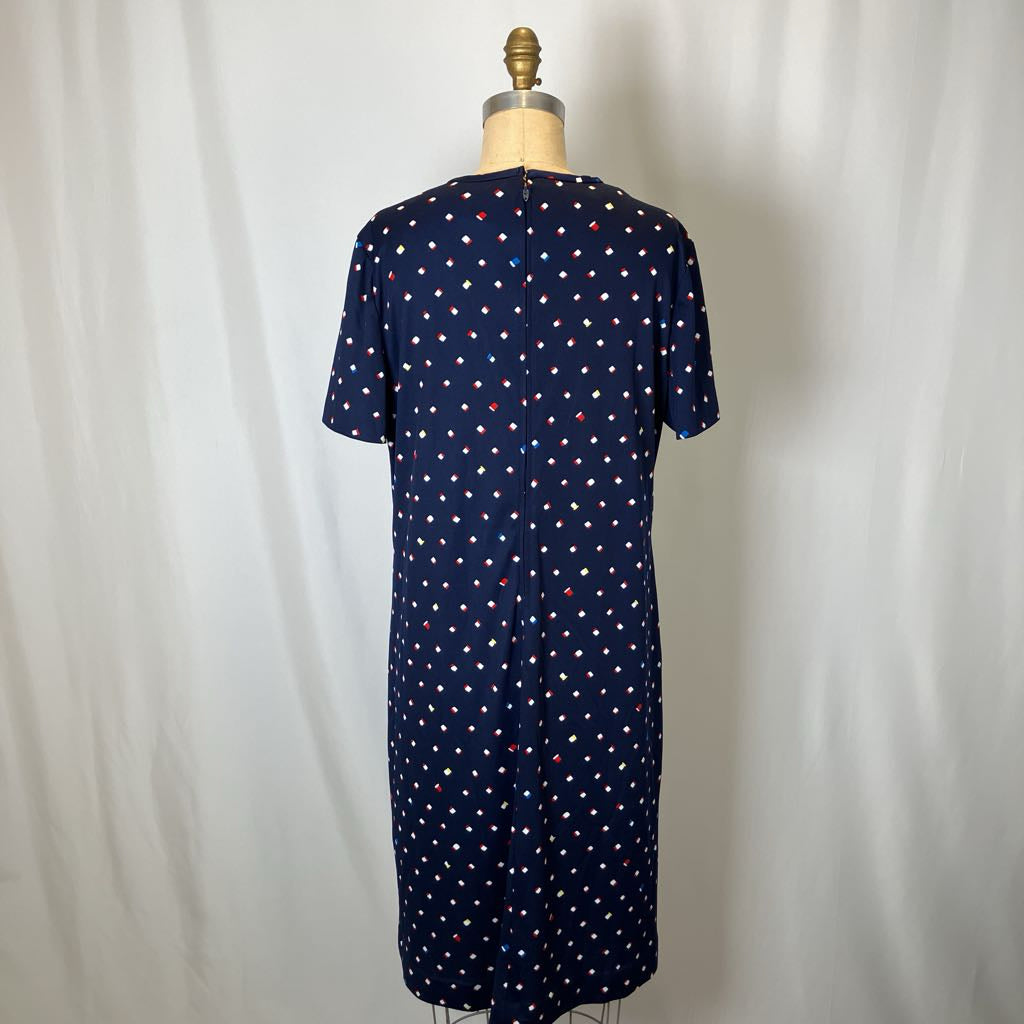 Navy dress with white polka dots on a mannequin against a white background