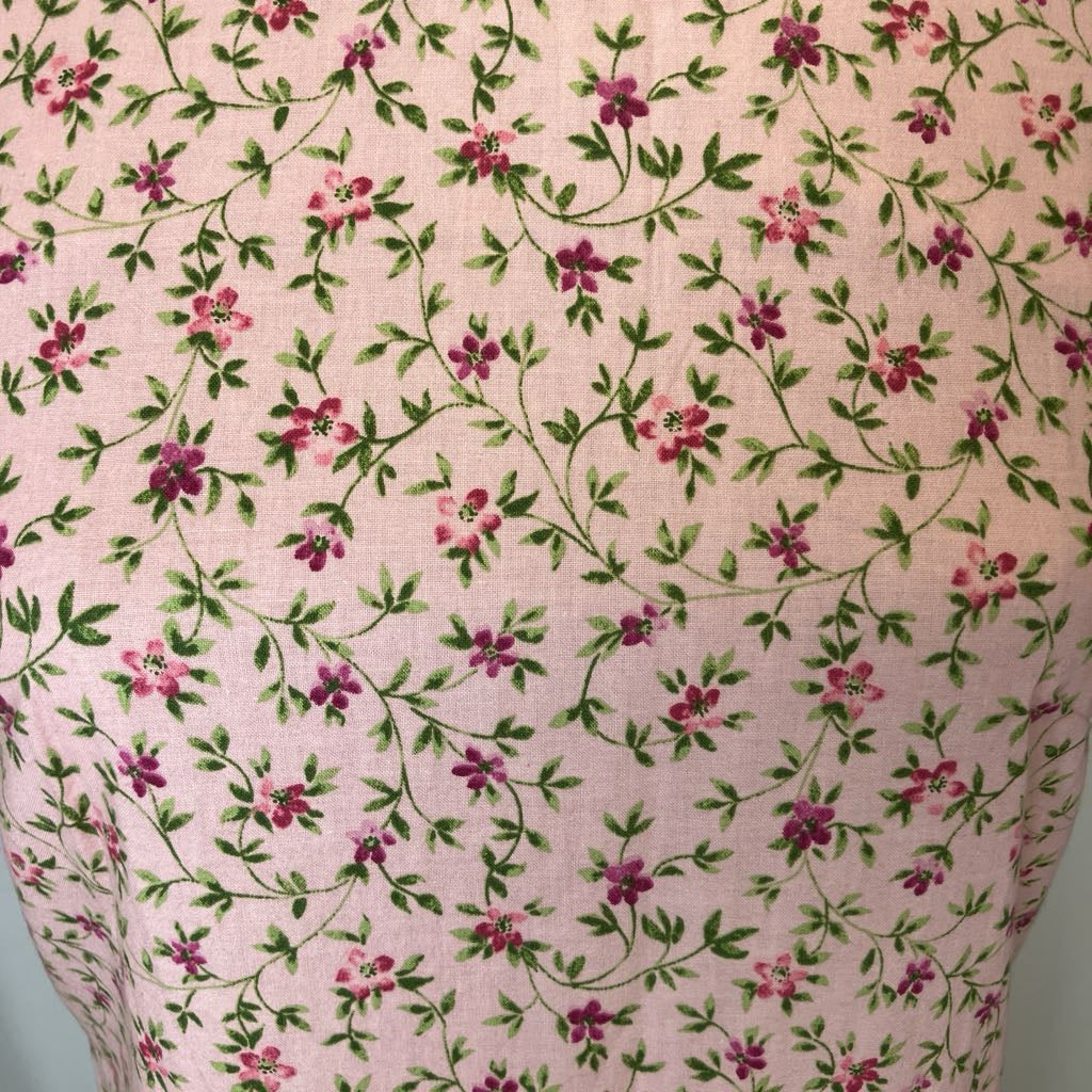 Floral patterned fabric with pink flowers and green leaves on a light pink background