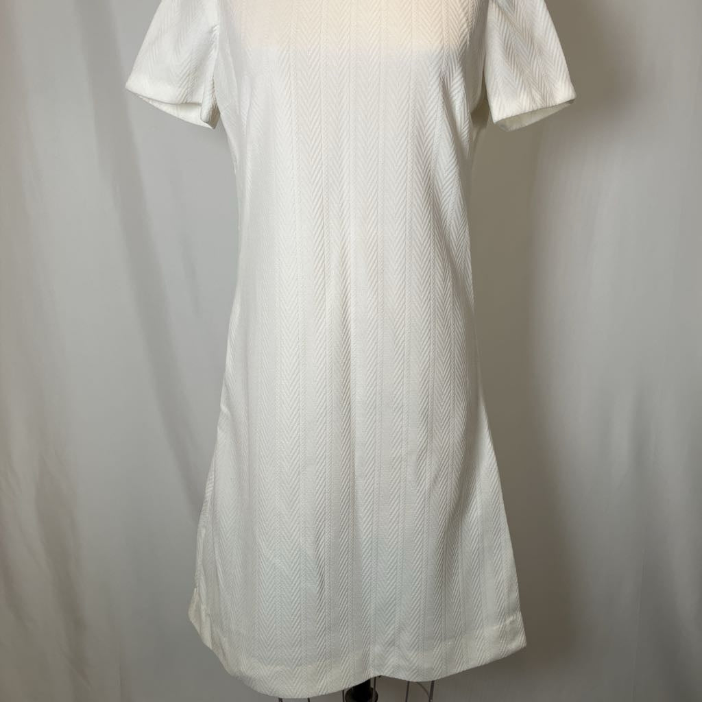 White textured dress on a mannequin against a plain background