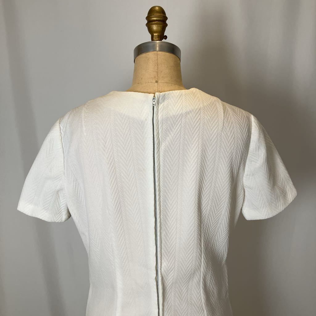 White textured dress on a mannequin against a plain background