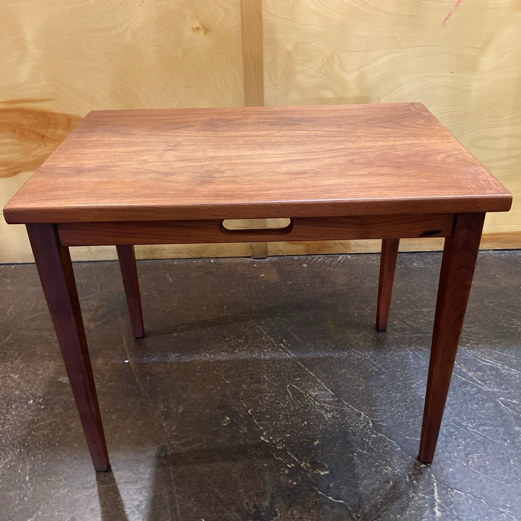 Wooden table with a drawer ledge on a reflective floor and wooden wall background