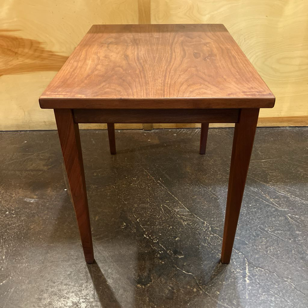 Wooden table with a brown finish on a reflective floor.