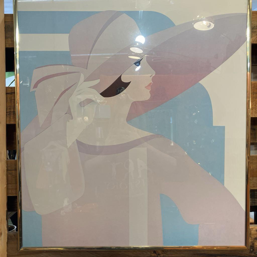 Framed artwork of a stylized woman with a large hat against a blue background.