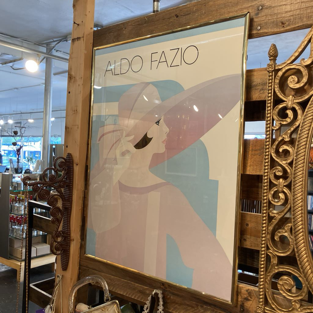 Framed poster of a woman with a hat by Aldo Fazio in a store setting.
