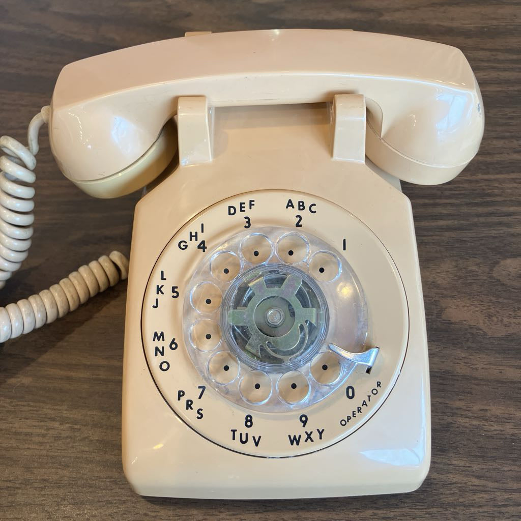 Beige rotary phone on a wooden surface
